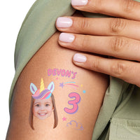 Custom unicorn Temporary tattoo with a child's face and 'Devon's 3' on a person's arm, with a hand touching the tattoo.