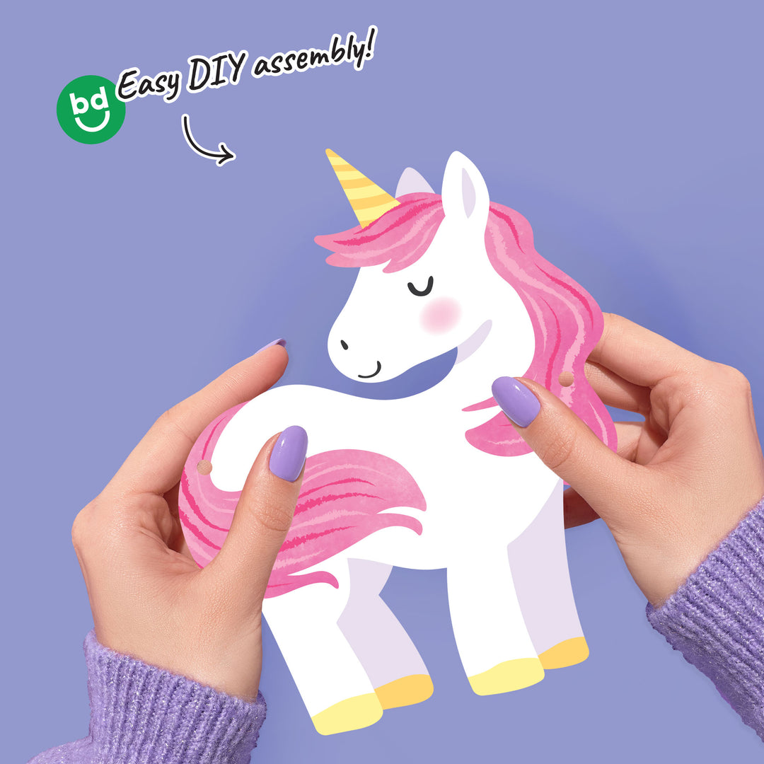 Unicorn-shaped product with pink hair and yellow horn, held by hands against a purple background, with 'bd' branding and 'Easy DIY assembly!' text.