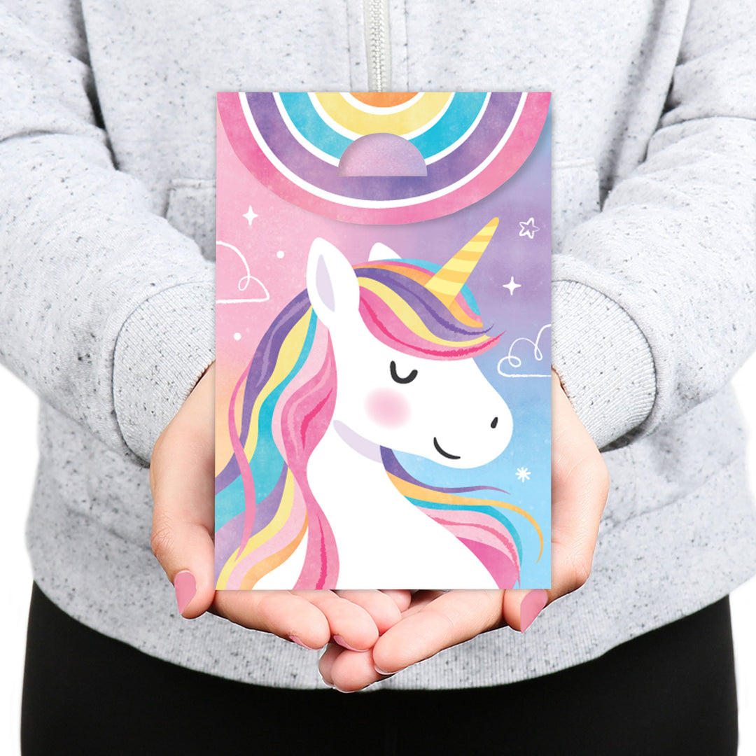 Person holding a colorful card with a unicorn design against a gray background