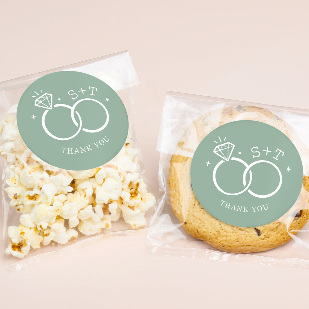 Popcorn and cookies in clear packaging with personalized green labels featuring a design of interlocking rings and text 'S + T THANK YOU'.