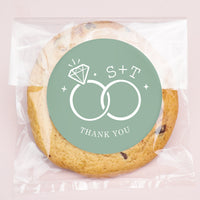 Cookie with a 'Thank You' label featuring initials and ring design on a pink background