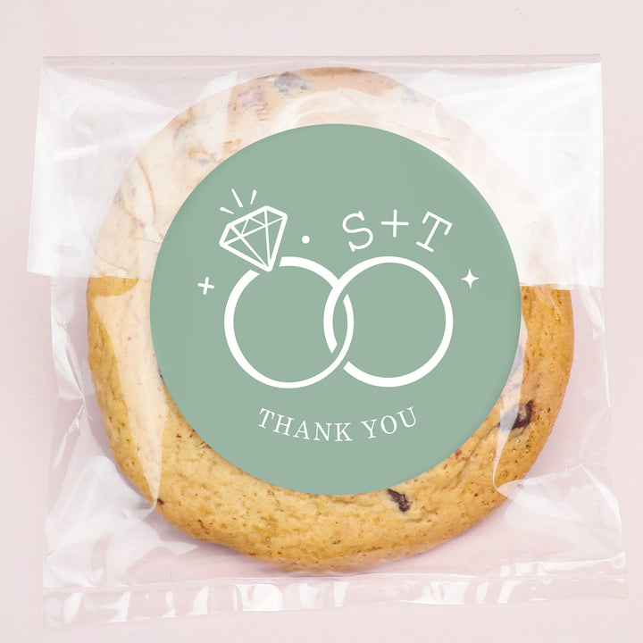 Cookie with a 'Thank You' label featuring initials and ring design on a pink background
