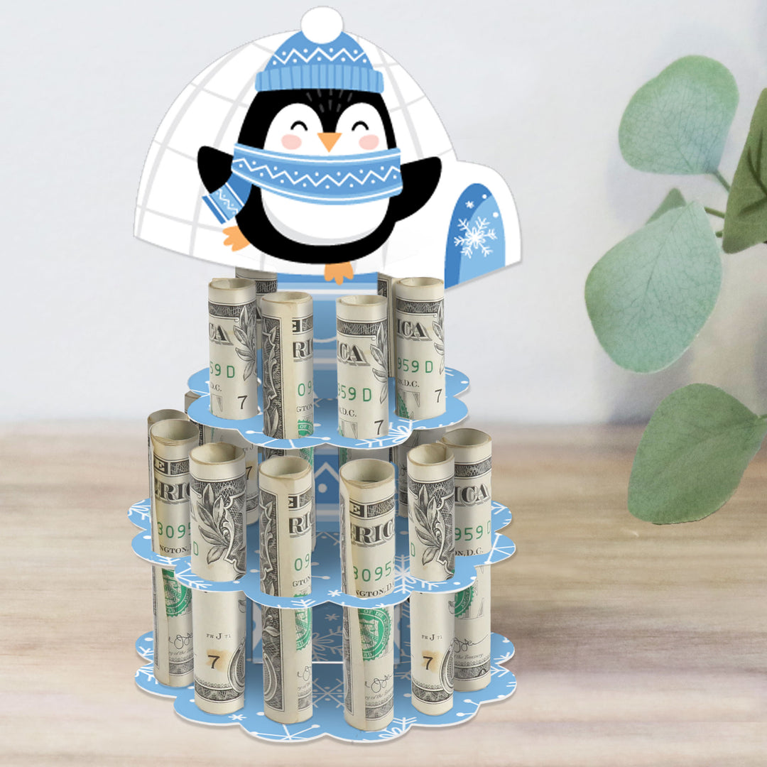 A decorative DIY penguin-themed money holder stand with slots for rolled-up bills, designed for use during holiday and Christmas parties.