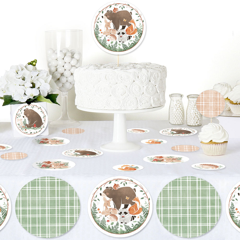 Woodland-themed party setup with cake, cupcakes, and decorative plates on a white tablecloth.