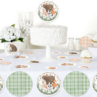Woodland-themed party setup with cake, cupcakes, and decorative plates on a white tablecloth.