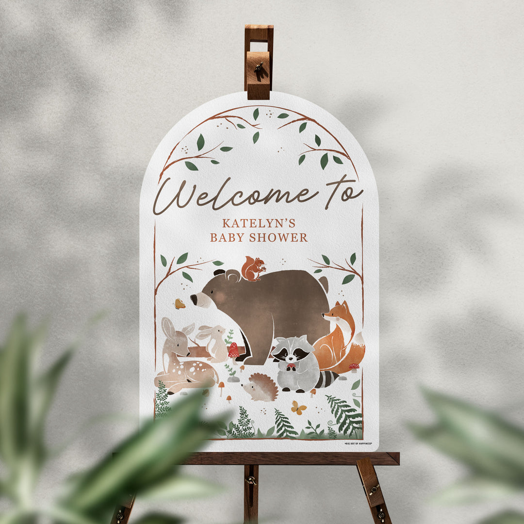 Woodland-themed baby shower welcome sign on an easel with a blurred natural background
