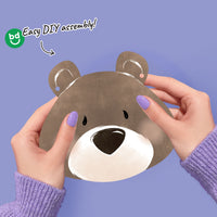 Bear baby shower decor with hands holding it against a purple background, featuring 'bd' branding.