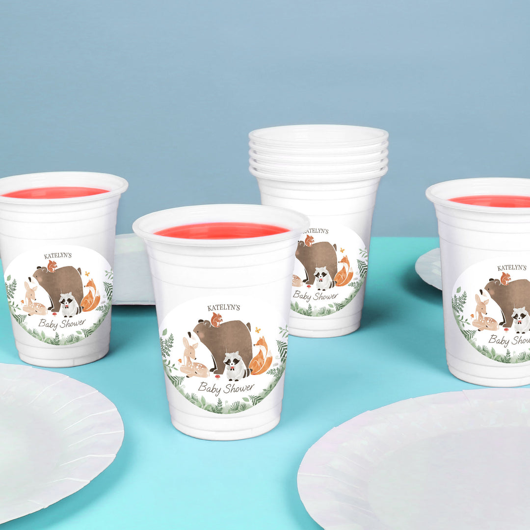 White cups with animal-themed designs forrest animal baby shower party essentials on a blue surface