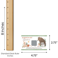 Scratch-off game with forest animals design next to a standard desk ruler for size reference.