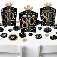 A set of adult 80th birthday party decorations in gold and black, including fold and flare table centerpieces and circular confetti.