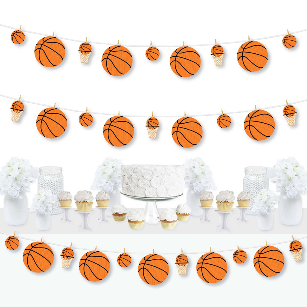 A basketball-themed clothespin garland banner featuring orange and white basketballs, displayed at a party with a cake and cupcakes in the foreground.