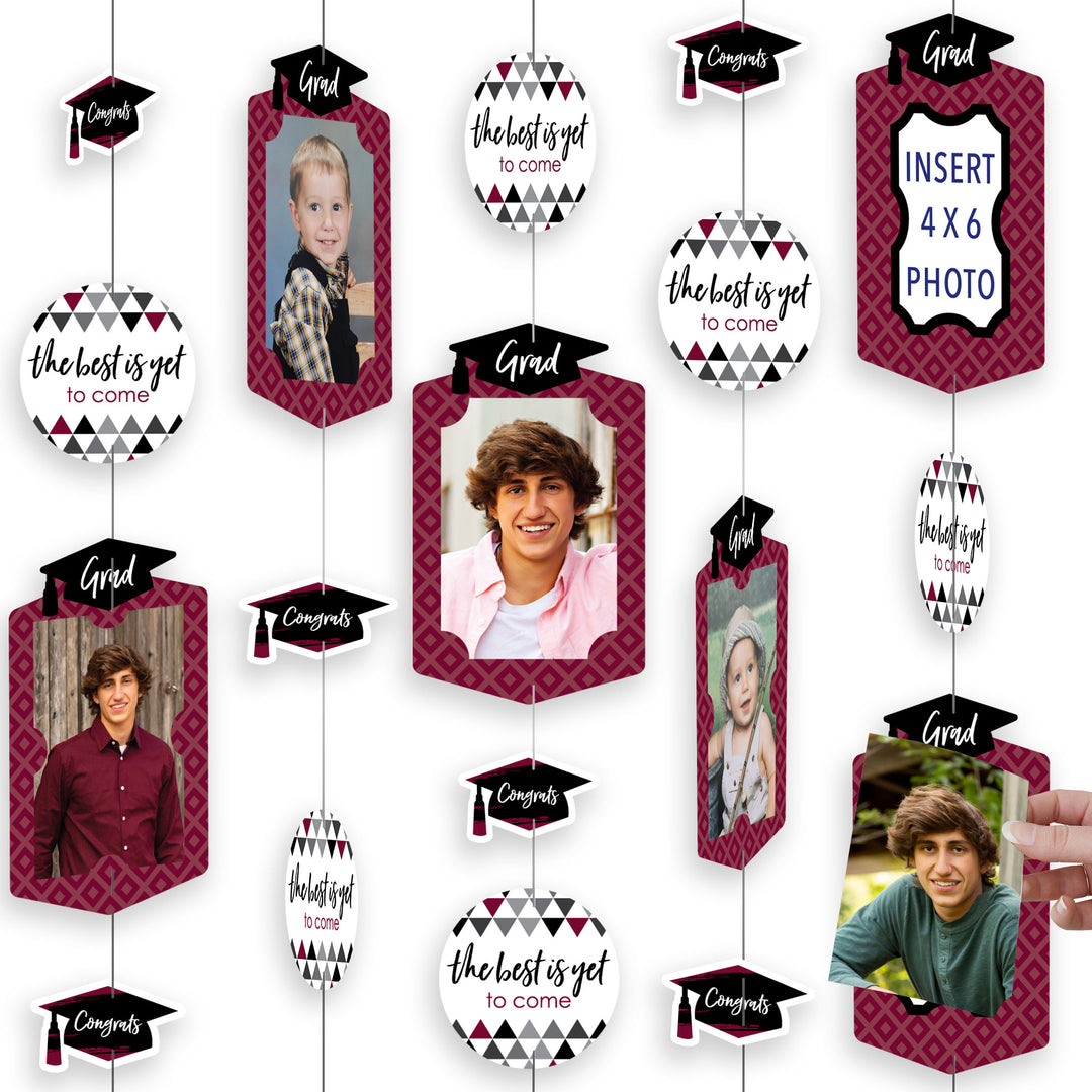 A collection of maroon colored graduation party decorations with cut-out shapes including frames, circles, and grad caps, arranged in a hanging vertical photo garland format.