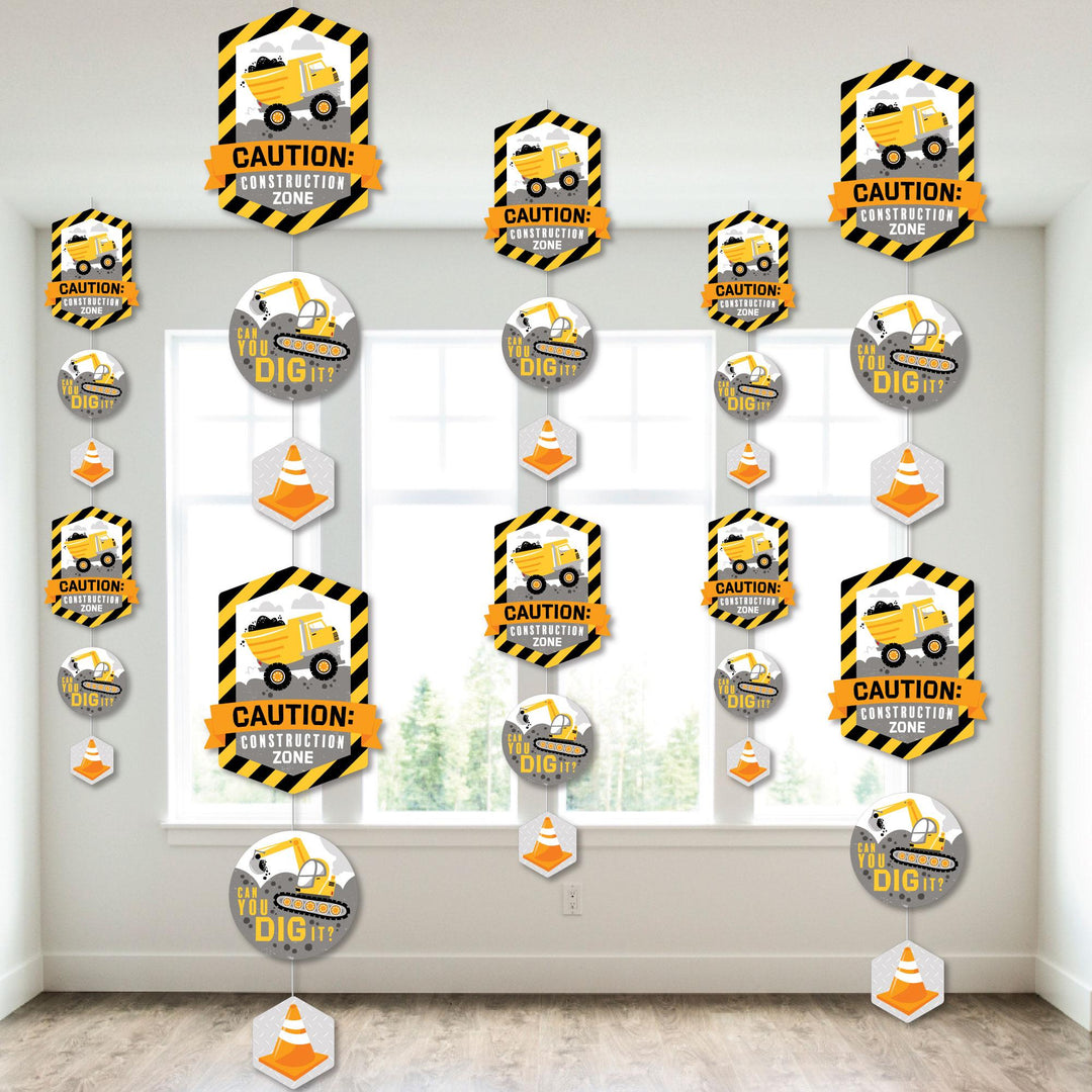 A set of construction-themed party decorations featuring various shaped pieces with a construction truck design, hanging from the ceiling.