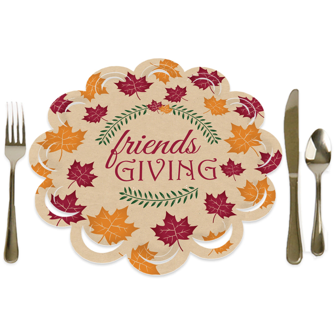 A round paper charger with a scalloped edge featuring the text 'friendsgiving' surrounded by leaf patterns. The charger is displayed with a fork on the left and a knife on the right, indicating a place setting.