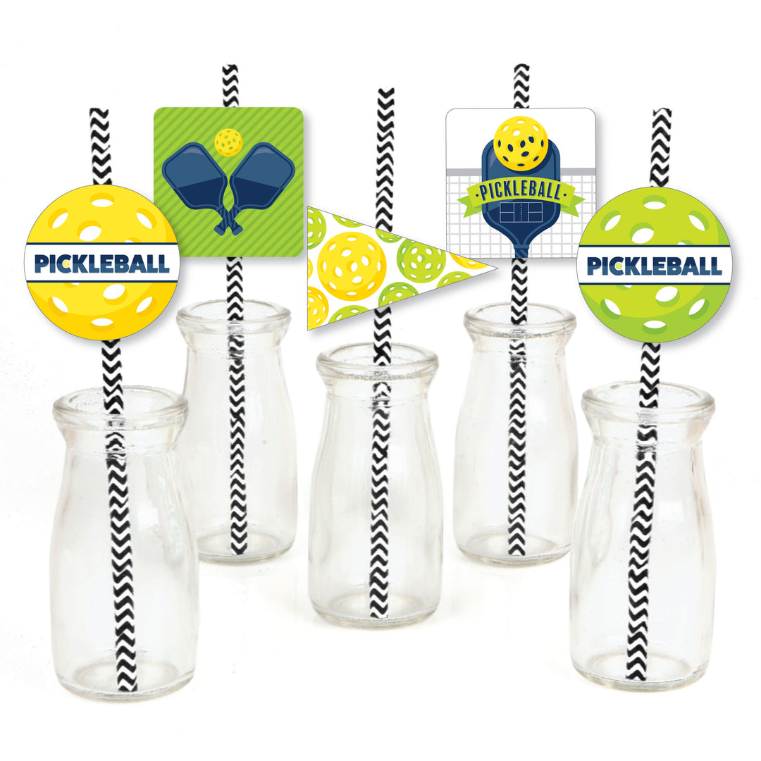 A set of paper straw decorations with striped patterns and pickleball-themed designs, including cut-outs of yellow and green pickleball shapes, pennants, and square shapes. The decorations are displayed in clear bottles and against a white background.