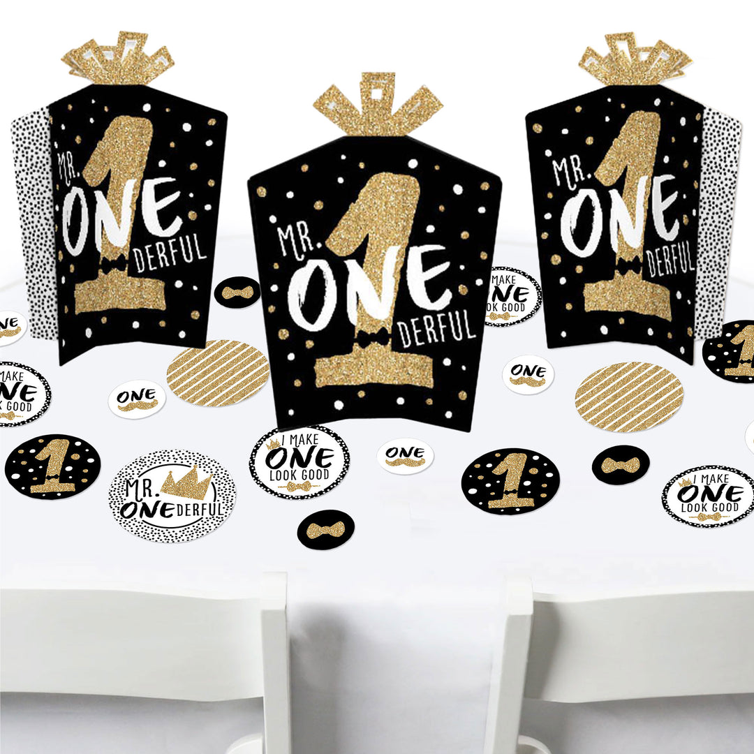 A set of birthday party decorations featuring black and gold colored elements with text reading 'Mr. Onederful'.