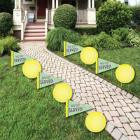 A set of 'You Got Served - Tennis' lawn decorations displayed on a garden path, consisting of yellow tennis ball and flag shaped signs with the text 'YOU GOT SERVED'.