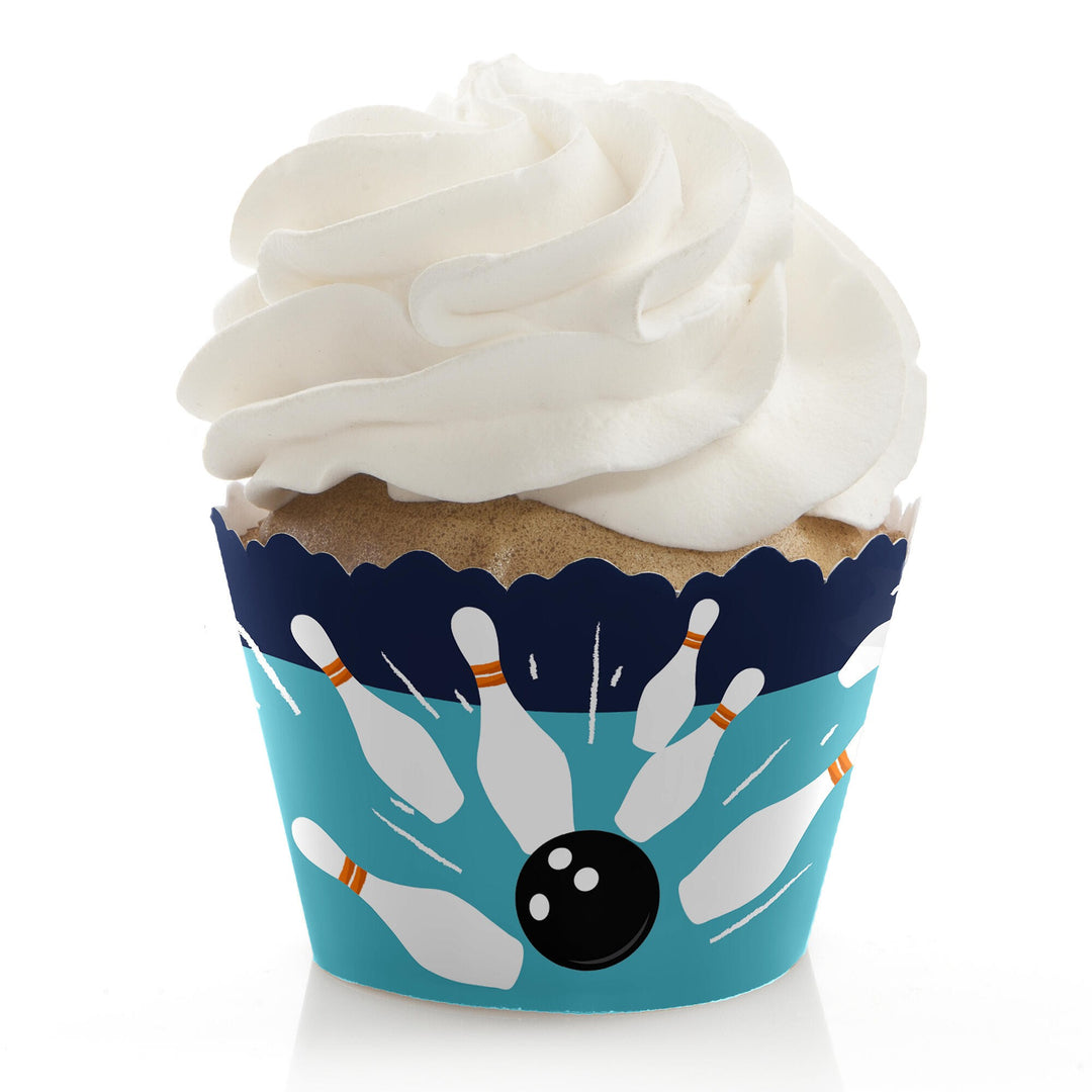 A cupcake with a blue cupcake wrapper featuring a bowling ball and pins pattern.