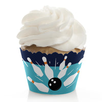A cupcake with a blue cupcake wrapper featuring a bowling ball and pins pattern.