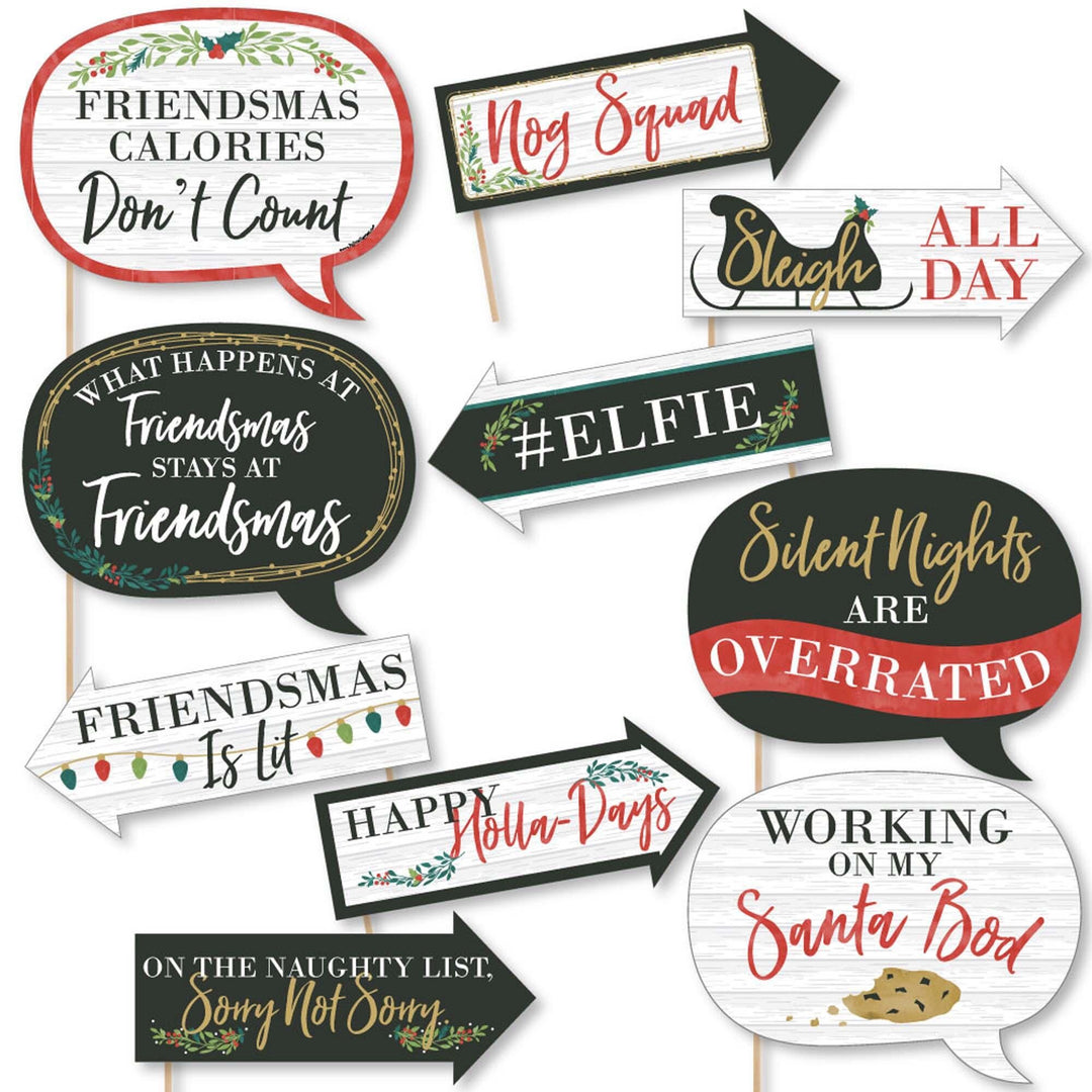 A collection of 10 printed and cut photo booth props with various humorous and festive phrases related to Christmas and friends, indicating a 'Merry Friendsmas' theme. Props are designed in different shapes and colors, some with arrows, and text phrases are written in different fonts and colors.