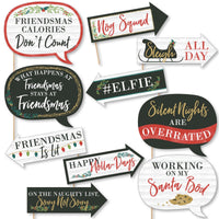 A collection of 10 printed and cut photo booth props with various humorous and festive phrases related to Christmas and friends, indicating a 'Merry Friendsmas' theme. Props are designed in different shapes and colors, some with arrows, and text phrases are written in different fonts and colors.