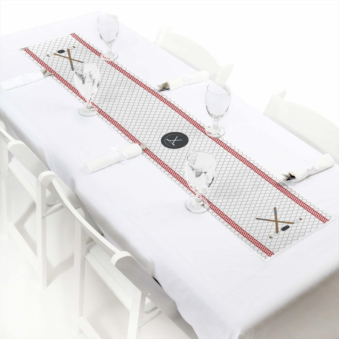 A paper table runner with a hockey theme, featuring red and white colors and decorative elements, laid out on a white tablecloth.