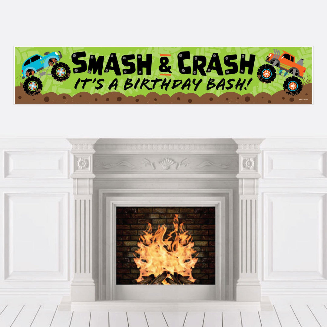A birthday banner with a 'Smash and Crash - Monster Truck' theme displayed over a fireplace, featuring colorful monster trucks and text.