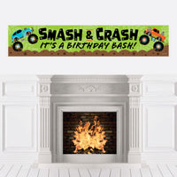 A birthday banner with a 'Smash and Crash - Monster Truck' theme displayed over a fireplace, featuring colorful monster trucks and text.