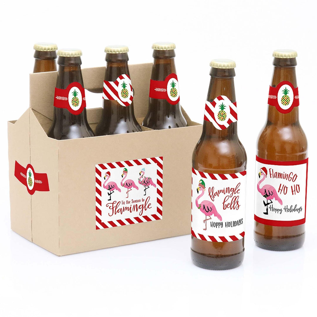 Six beer bottle labels with tropical flamingo design, attached to bottles in a kraft paper carrier, indicating the product is Christmas-themed.