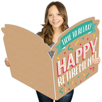A person holding a large, colorful greeting card with 'HAPPY RETIREMENT' written on it.