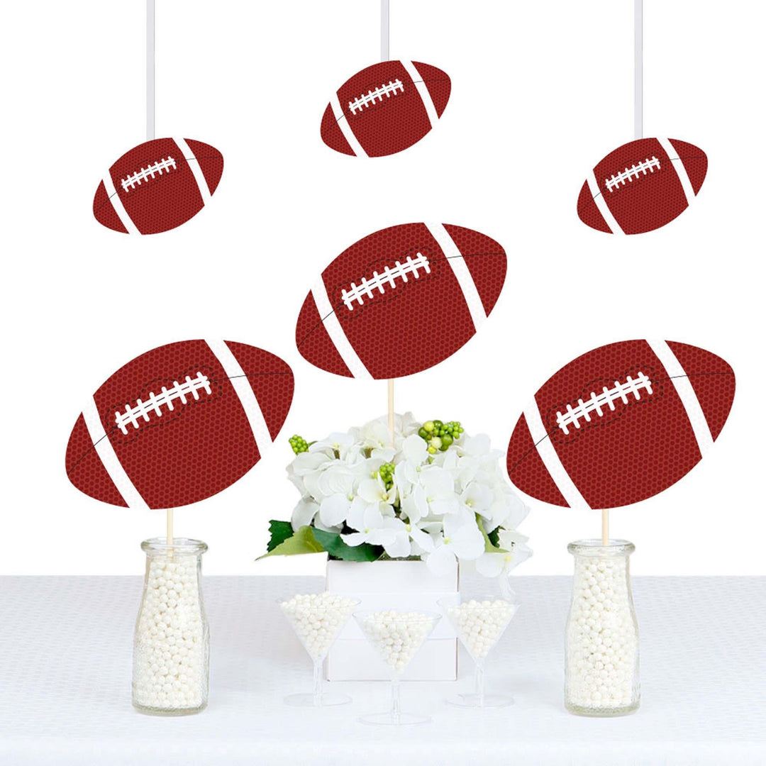 A set of football-shaped party decorations displayed over a table with a floral centerpiece.