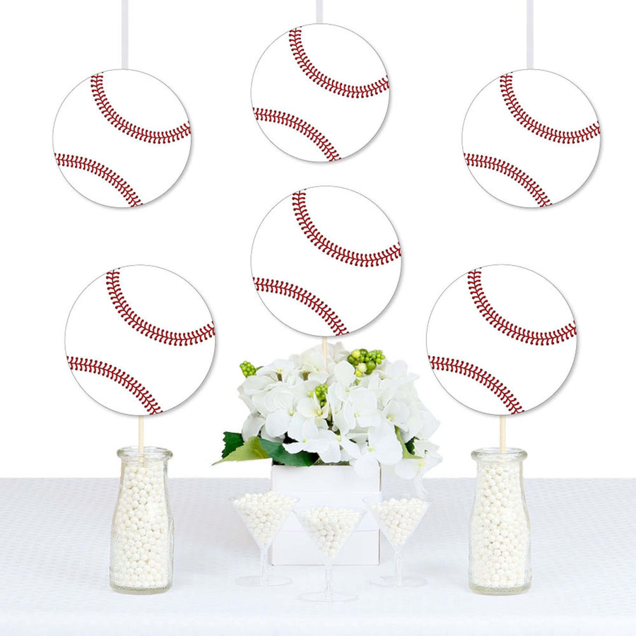 A set of paper cutouts shaped like baseballs, with a red stitching pattern, used as decorations for a party displayed above a table.