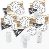 A set of volleyball-themed centerpiece sticks with various designs including a volleyball net and text 'Bump Set Spike'. They are displayed in jars and vases, indicating usage for table decoration.