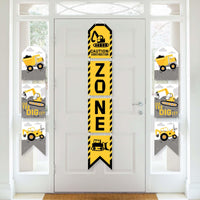 A set of vertical hanging paper banners with construction theme, including a 'ZONE' banner and others with construction vehicles and tools, displayed on a white door.