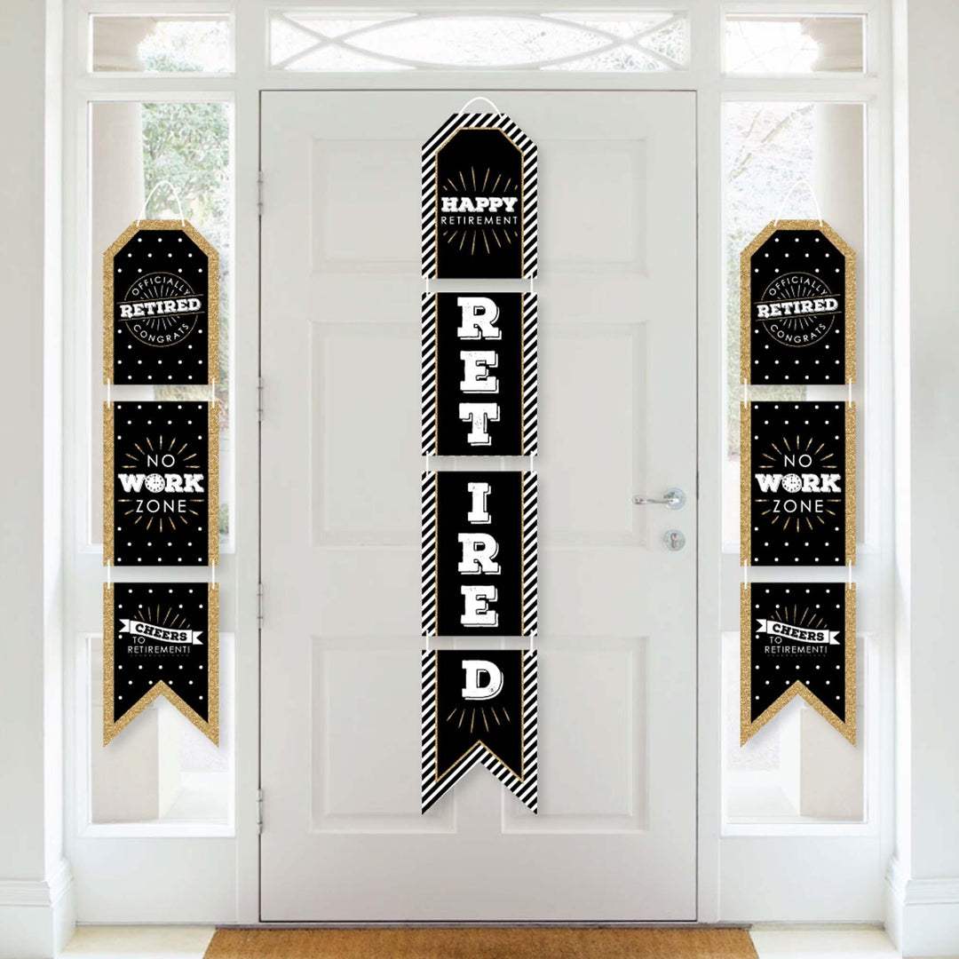 A set of vertical hanging paper banners with 'HAPPY RETIRED' text arranged in a sequence on a white door, decorated with black and gold patterns.