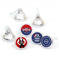 A collection of round candy stickers with various wrestling-themed designs, including a character in a red and black suit, and logos with a mat and wrestling elements. The candies are designed to fit on Hershey's Kisses.